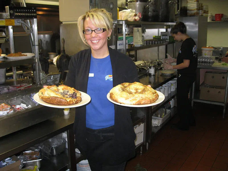 Server carrying two golden baked pancakes out of the kitchen