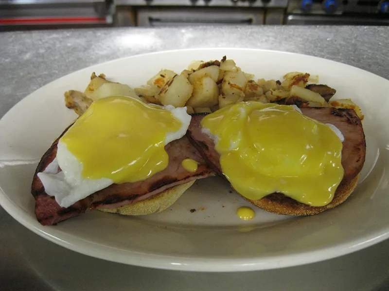 Eggs Benedict with grilled ham and hollandaise over home fries