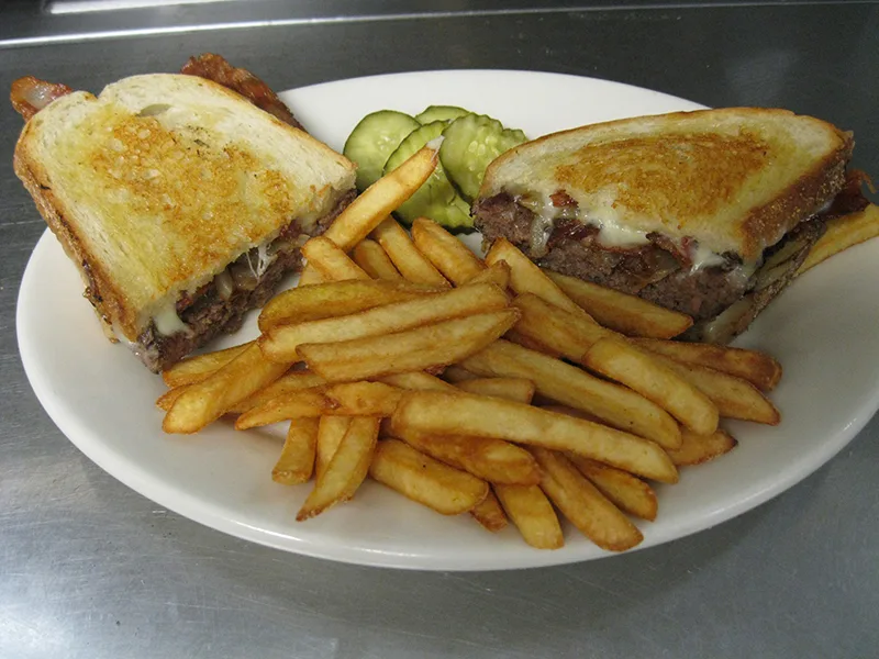 Patty melt on grilled rye with a pile of French fries