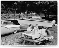 Vintage photo of a picnic beside a classic car and a boat